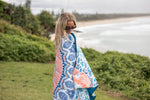Sustainable down puffy blanket with blue, coral, and white geometric pattern, draped over shoulder outdoors. preview #4