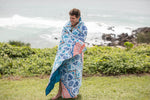 Sustainable down puffy blanket with blue and orange geometric print, wrapped around man at beach preview #6