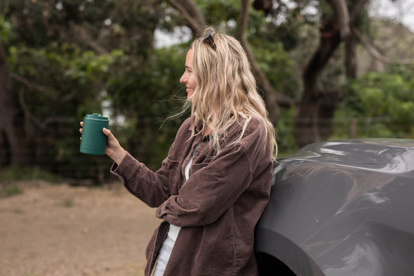 Jungle Green insulated coffee cup lid held by woman outdoors, cylindrical design with secure closure