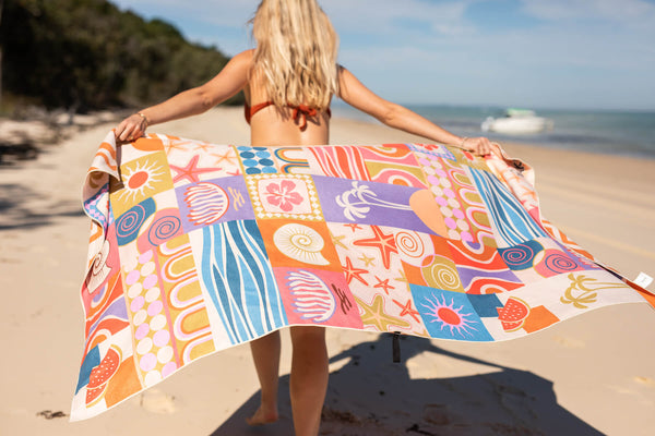 Colorful patchwork beach towel with retro sun, starfish, and geometric patterns in orange, blue, purple