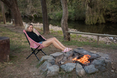 Rosy Tides Camping Chair beside a riverside campfire