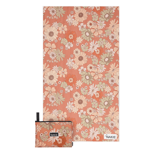 Coral recycled beach towel with multicolored daisy and wildflower pattern, shown folded with matching pouch.